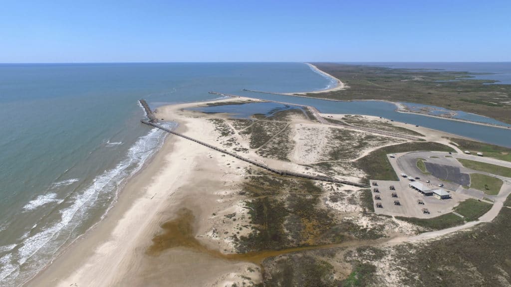 Sunrise at Jetty Park walkway with anglers and surf at Matagorda Beach, Texas